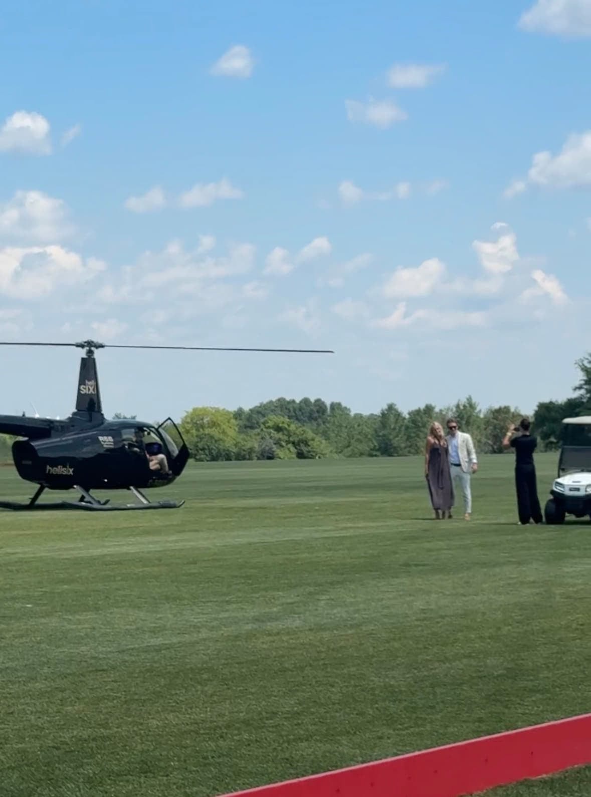 A helicopter on a clipped lawn beside a black car